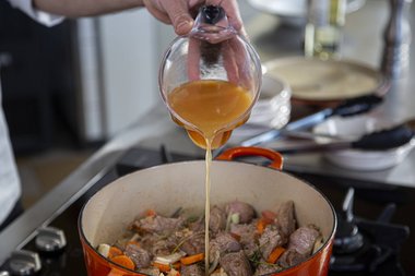 Fügen Sie die Bouillon hinzu an den Kalbfleisch..